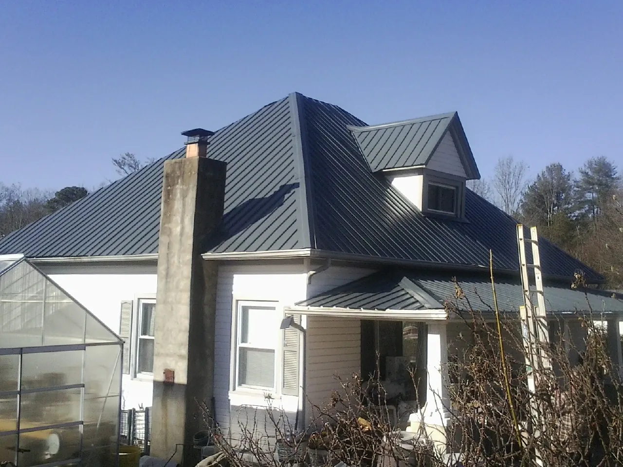 Dark blue standing seam metal roof on a white farmhouse with dormer — Slate & Tile Roof Repair by Roofing Brothers in Wills Point