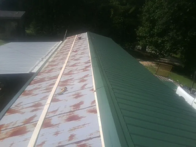 Old rusted panels beside newly installed green metal roofing — Wind Damage Roof Repair by Roofing Brothers in Wills Point
