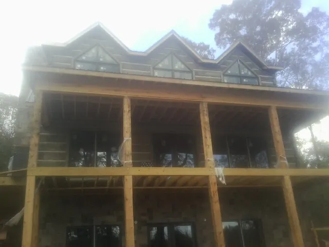Dormers and porch framing on a large log home under construction — Roof Coating work by our crew in Wills Point