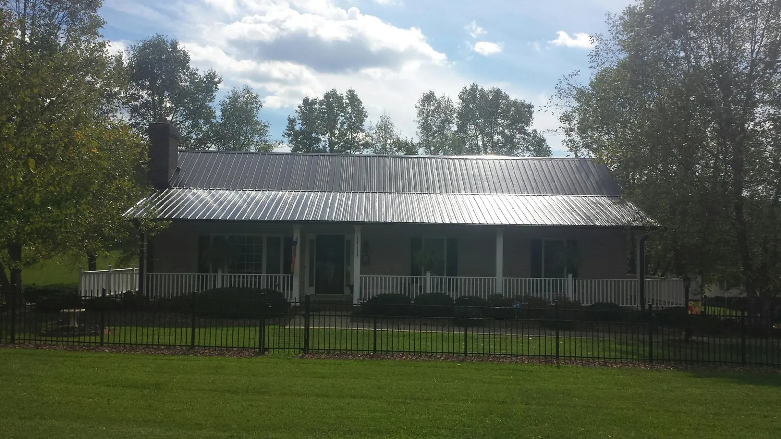 Gray metal roof on a brick ranch with a full width front porch — Gutter Guard Installation work by our crew in Wills Point
