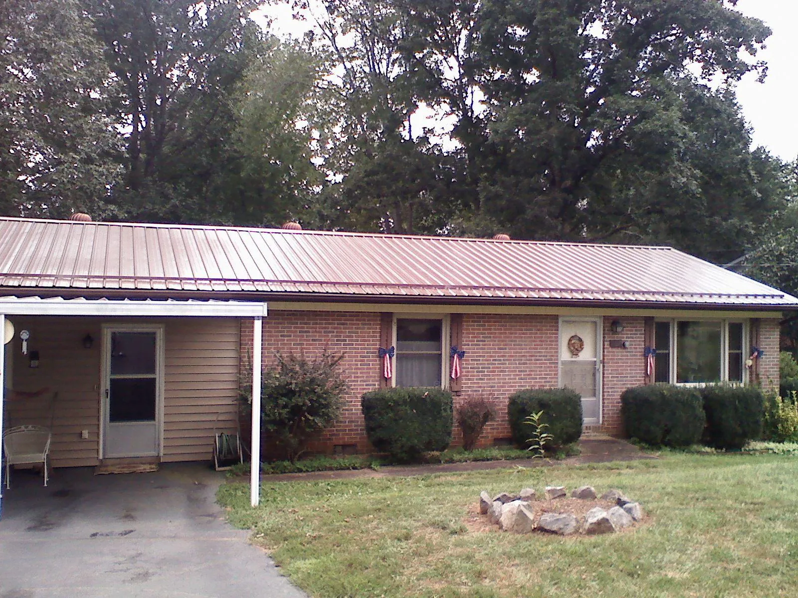 Bronze metal roof and carport on a brick ranch home — Roof Repair work by our crew in Wills Point