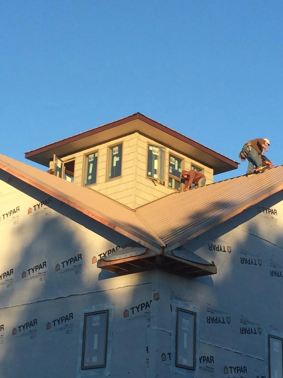 Roofers working around a rooftop cupola on a new metal roof at sunset — Roof Waterproofing in Wills Point by Roofing Brothers